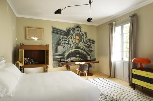 Modern bedroom at Mas De Lafeuillade in Montpellier with pale yellow walls, white bedding, statement mirror art, and
