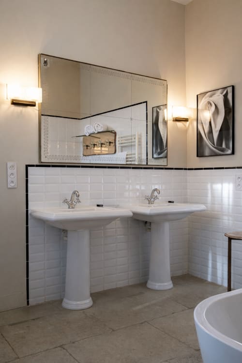 Elegant bathroom with dual pedestal sinks, white subway tiles, and decorative mirrors at Mas De Lafeuillade, Montpellier