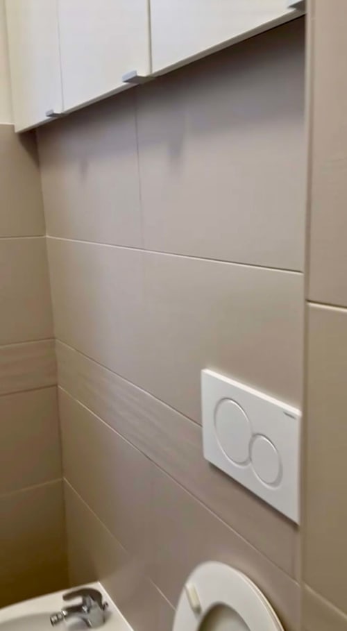Modernes Badezimmer in den Magnolia Apartments Mailand mit gefliesten Wänden, Toilette und Doppelspültaste