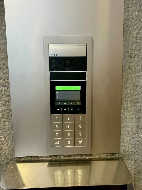 Cornell-Videosprechanlage mit Tastenfeld an weißer Wand in der Eingangshalle von Magnolia Apartments Mailand, mit Kamera und Ruftaste