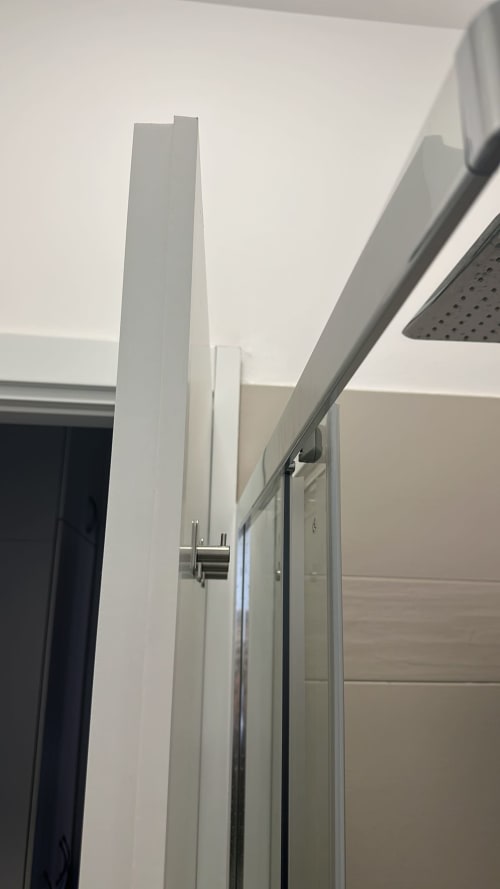 Moderner Badezimmereingang in Mailänder Apartment mit weißem Waschbecken, verchromten Armaturen und Duschbereich