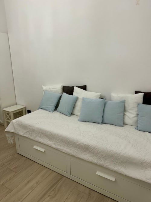 Stilvolles Schlafzimmer im Magnolia Apartments Milan mit weißem Plattformbett, blauen und cremefarbenen Kissen, Holzboden und modernem Design