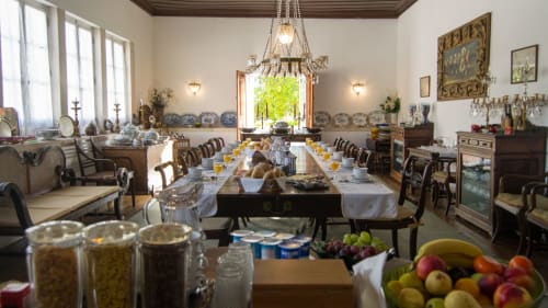 Elegant dining room at Quinta da Alcaidaria-Mór with long table, crystal chandelier, and fresh fruit display in Fátima