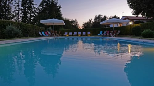 Twilight view of Quinta da Alcaidaria-Mór's pool in Fátima, Portugal, with loungers and umbrellas