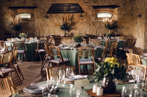 Elegante sala de refeições na Quinta da Alcaidaria-Mór em Fátima com paredes de pedra rústica, cadeiras de madeira e toalhas verdes