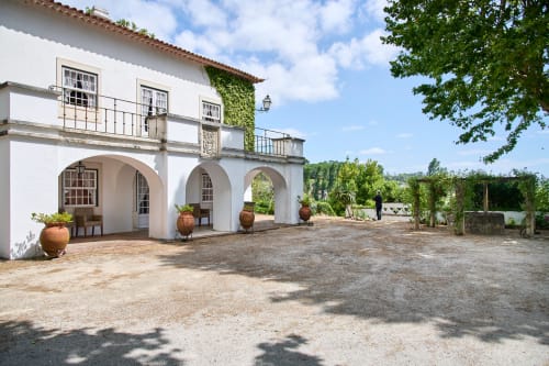 Pátio da Quinta da Alcaidaria-Mór com arcos brancos, jarros de barro e jardins verdes em Ourém-Fátima, Portugal