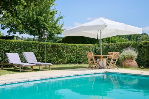 Quinta da Alcaidaria-Mór pool area in Ourém with loungers, umbrella, and green hedges