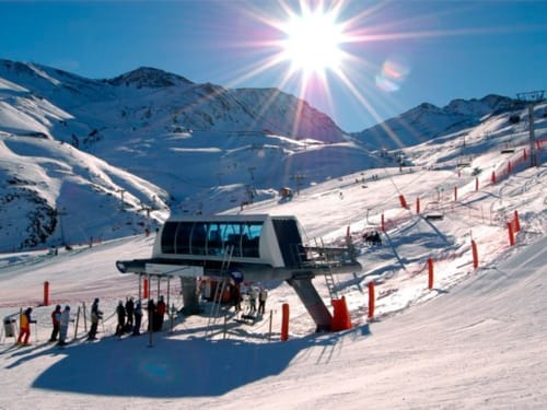 Station moderne de remontée mécanique à l'hôtel Flor de Neu avec pistes enneigées et montagnes sous le soleil brillant à El Pont de Suert