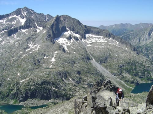 Randonneurs alpins sur un terrain rocheux montagneux avec pics, plaques de neige et lacs turquoise près d'El Pont de Suert, Espagne