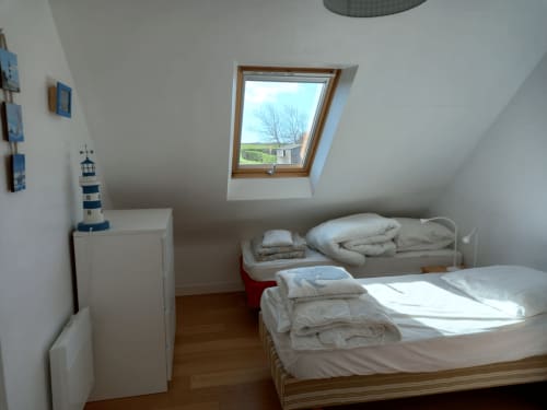 Chambre mansardée lumineuse du gîte Belle Île avec puits de lumière, lit double, lit simple et vue jardin par fenêtre de toit