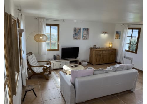 Salon lumineux avec canapé blanc, téléviseur, mobilier bois et vue sur jardin à Locmaria Belle Île en Mer