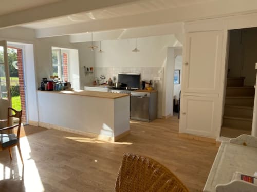 Cuisine et salle à manger modernes du gîte Belle Île en Mer avec cabinetry blanc, appareils inox et parquet