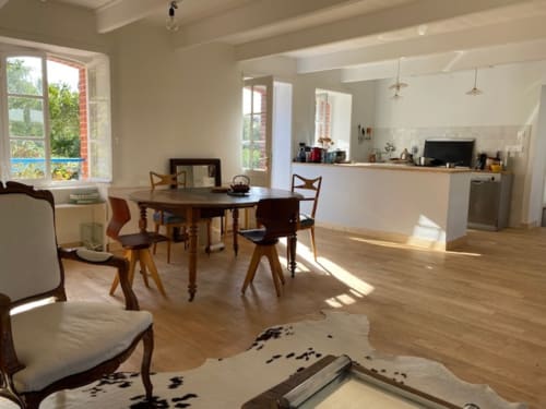 Salle à manger et cuisine lumineuse et aérée avec table en bois, vue sur le jardin par les fenêtres, Belle Île en Mer