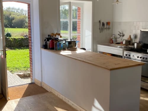Cuisine moderne de charme avec îlot en bois, vue sur le jardin par portes-fenêtres à Locmaria Belle Île en Mer