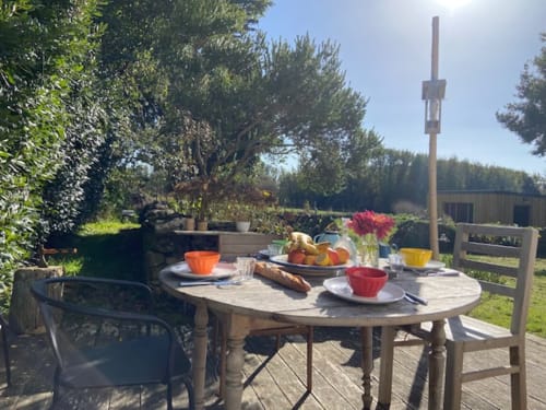 Table de jardin dressée avec assiettes colorées et fleurs sur la terrasse de la chaumière Locmaria, Belle Île-en-Mer