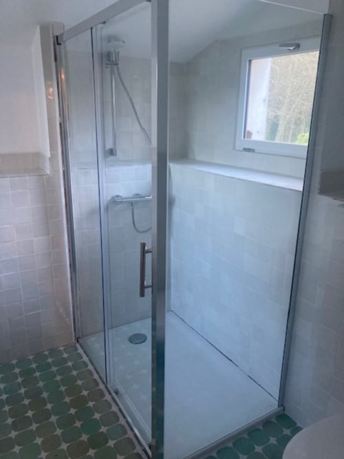 Douche moderne aux portes vitrées dans salle de bains de cottage à Locmaria, Belle Île en Mer, avec carrelage et jardin