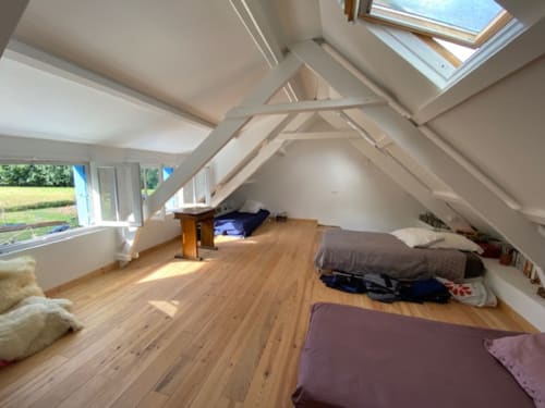 Chambre mansardée spacieuse avec parquet, plafond incliné, lucarne, lits et vue sur le jardin du gîte Locmaria