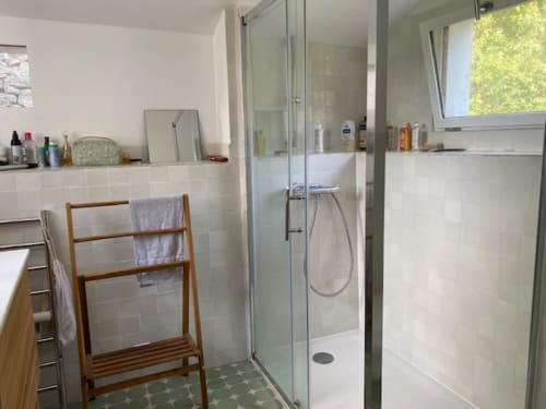 Salle de bains moderne avec douche à l'italienne, carrelage blanc, porte-serviettes en bois et équipements au gîte Locmaria sur Belle Île en Mer