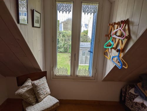 Chambre lumineuse à Locmaria, Belle-île-en-Mer, avec poutres en bois, vue sur le jardin par grandes fenêtres et colorée