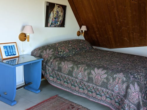 Chambre douillette avec literie à motifs, bureau bleu, plafond bois et appliques laiton à Locmaria Belle Île en Mer