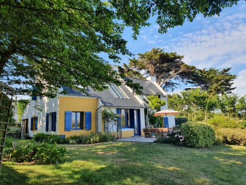 Charmante maison de vacances jaune et blanche aux volets bleus à Locmaria, Belle-Île-en-Mer, entourée de jardins luxuriants