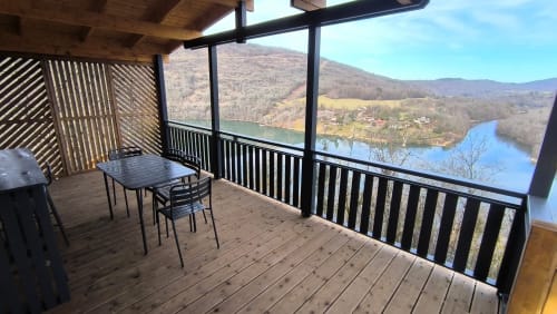 Scenic deck of Lodge LE CHAMOIS overlooking Ain River valley with mountains, featuring dining area and black railings