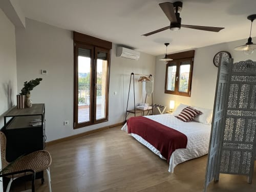 Dormitorio moderno con vistas emblemáticas en apartamentos AlmaMaterSalamanca en Salamanca, con suelos de madera y acceso a terraza