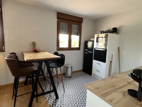Cocina y comedor modernos en Salamanca con mesa de madera, sillas negras y electrodomésticos de acero inoxidable