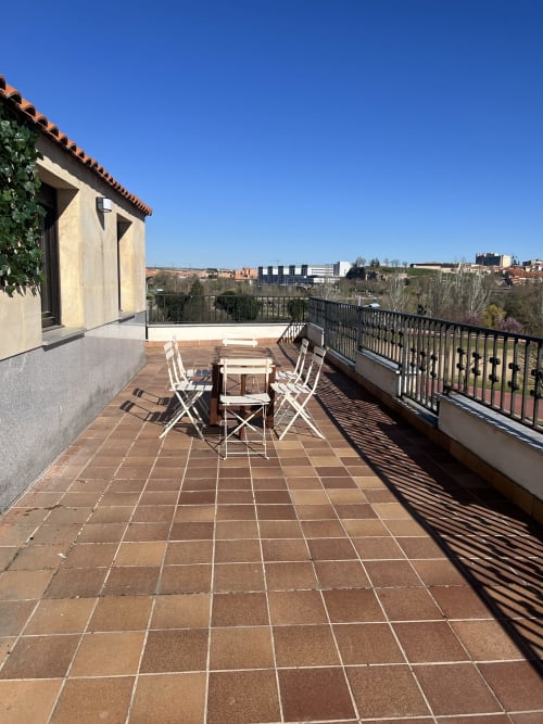 Amplia terraza en la azotea de AlmaMaterSalamanca con zona de comedor con vistas al paisaje urbano de Salamanca