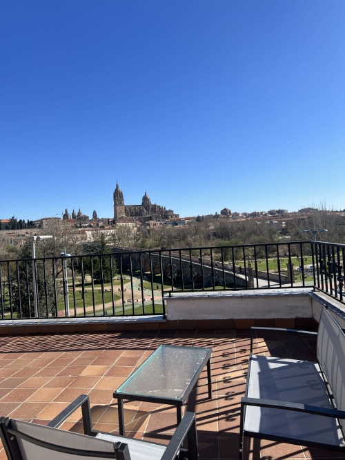 Terraza de apartamento con vistas al icónico Catedral de Salamanca y horizonte urbano bajo cielo azul despejado