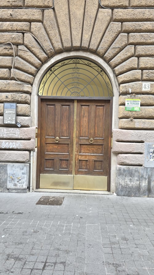 Ingresso dell'appartamento Zoelia nel rione Vaticano: portone doppio in legno con arco ornamentale nel palazzo storico romano