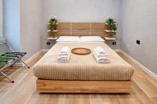 Camera moderna a Zoelia Rome con letto in legno, biancheria beige, piante in vaso e pavimento in parquet nella zona Vaticano