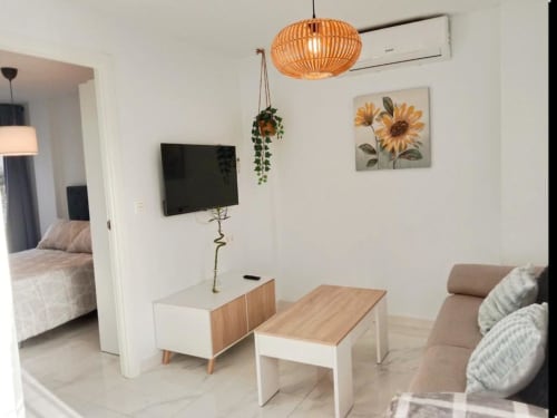 Moderno salón en Top Home Integra, Jerez de la Frontera, con muebles de madera, plantas colgantes y girasol