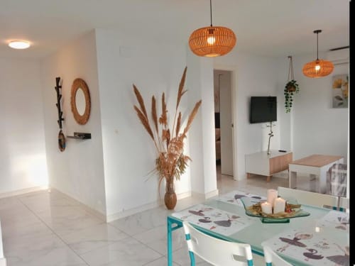 Interior moderno de apartamento en Jerez con comedor, lámparas colgantes tejidas, decoración de pampas secas y muebles inspirados en la costa