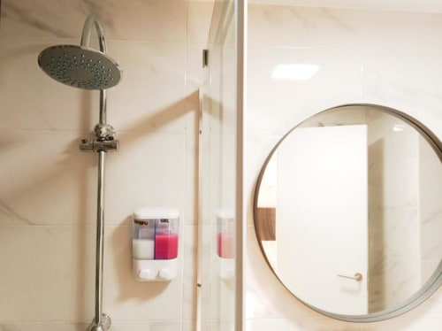 Moderno baño con ducha de lluvia y espejo redondo en apartamento Top Home Integra, Jerez de la Frontera