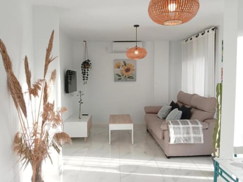 Luminoso salón en Top Home Integra, Jerez con sofá beige, lámparas colgantes, plantas y decoración moderna