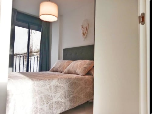 Dormitorio moderno del apartamento Top Home Integra en Jerez de la Frontera con vistas a la ciudad, cabecero verde y acceso a balcón
