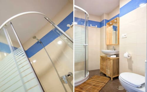 Baño moderno en Ab Be Penthouse, Málaga con azulejos azules y crema, ducha de cristal curvo, tocador de madera, inodoro y