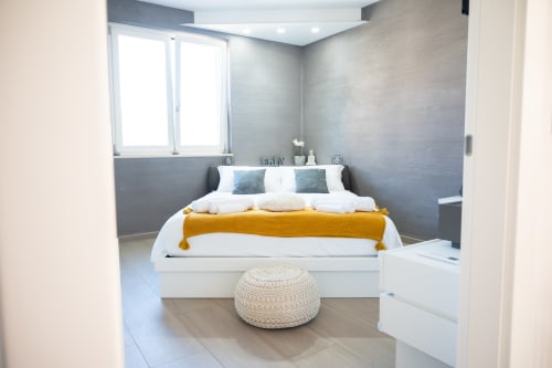 Camera moderna dell'hotel L.H.A. a Ferrara con letto bianco, accenti blu e plaid color senape