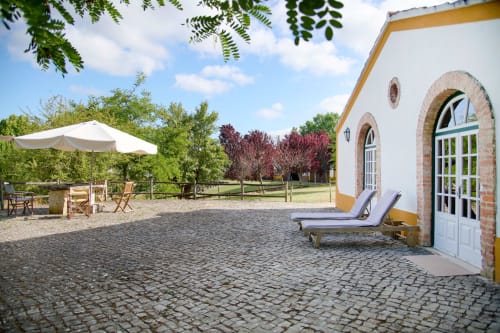 Pátio da Quinta da Alcaidaria-Mór com espreguiçadeiras, edifício branco e paisagem rural perto de Fátima