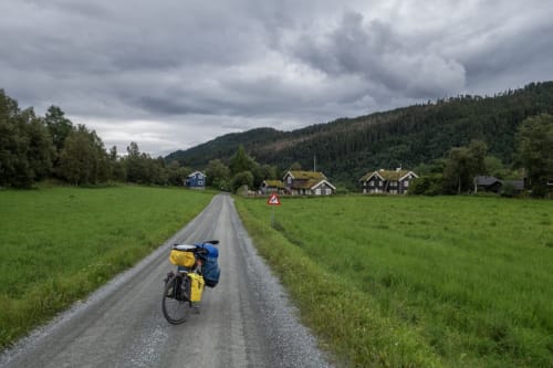 Loaded bicycle on rural gravel road leading to traditional Nordic houses in Sépeaux Saint Romain, France