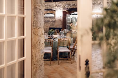 Sala de jantar rústica na Quinta da Alcaidaria-Mór com paredes de pedra, cadeiras de madeira e mesas elegantemente postas em Fátima,