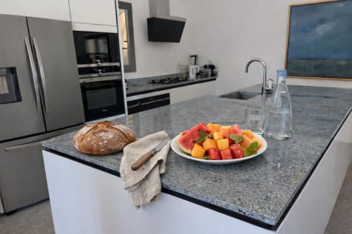 Cuisine moderne de la Villa Marine avec îlot en granit, fruits frais, pain artisanal et électroménagers inox.