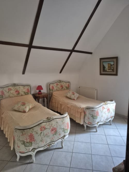 Chambre avec deux lits jumeaux, têtes de lit florales et plafond à poutres au gîte Le Moulin Garnier à Vernou-sur-Brenne