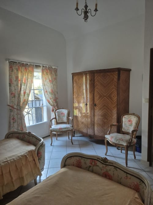 Chambre élégante au gîte Le Moulin Garnier à Vernou sur Brenne avec fauteuils fleuris, armoire en bois et vue sur la rivière