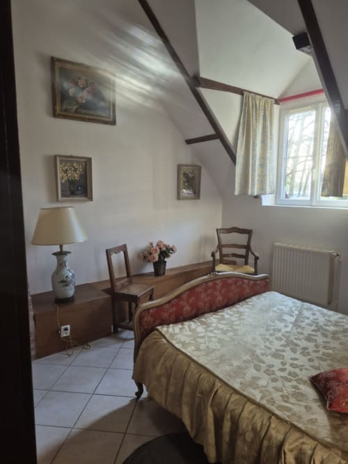 Chambre du gîte Le Moulin Garnier à Vernou sur Brenne avec poutres apparentes, mobilier d'époque et vue sur la rivière