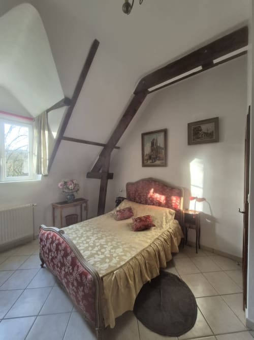 Chambre mansardée au Moulin Garnier avec poutres apparentes, mobilier d'époque et vue sur la rivière