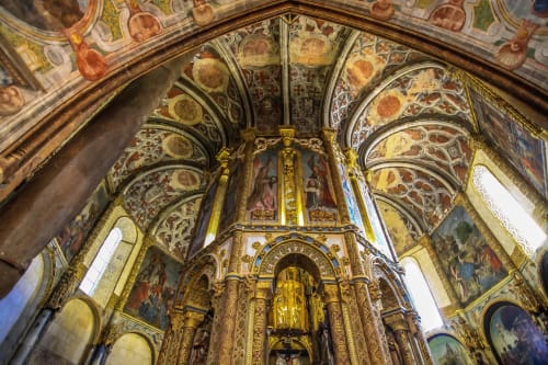 Interior de capela barroca ornamentada com altar de madeira dourada, afrescos no teto pintado e detalhes de abóbada em arco na Quinta da