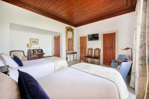 Elegant bedroom at Quinta da Alcaidaria-Mór in Ourém-Fátima with two beds, wooden ceiling, and classic Portuguese furnishings