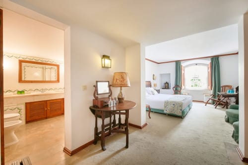 Quinta da Alcaidaria-Mór bedroom suite in Ourém-Fátima with bathroom, sitting area, and bed with green accents